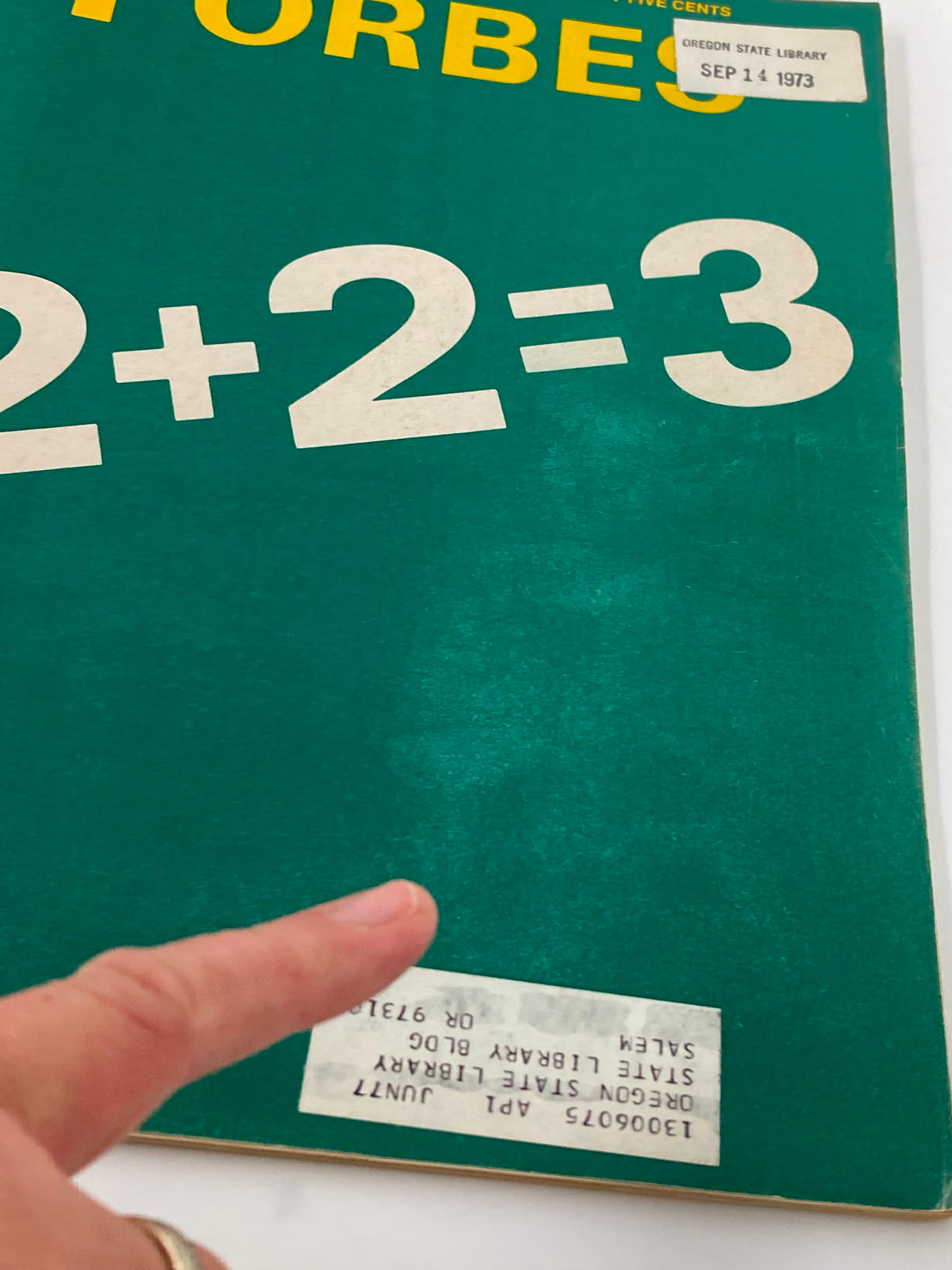 Close-up of the cover of VTG Forbes Magazine September 15, 1973, highlighting the title '2+2=3' and library stickers affixed to the magazine.