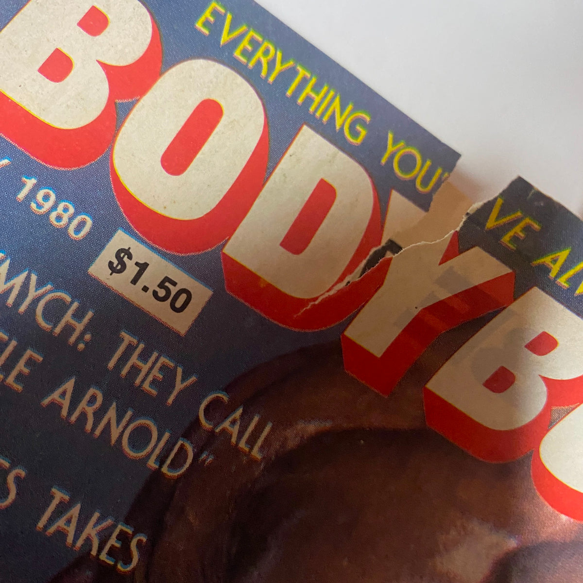 Close-up showing damage to the cover of Bodybuilder Magazine May 1980, emphasizing visible wear with a focus on the publication's vintage condition.