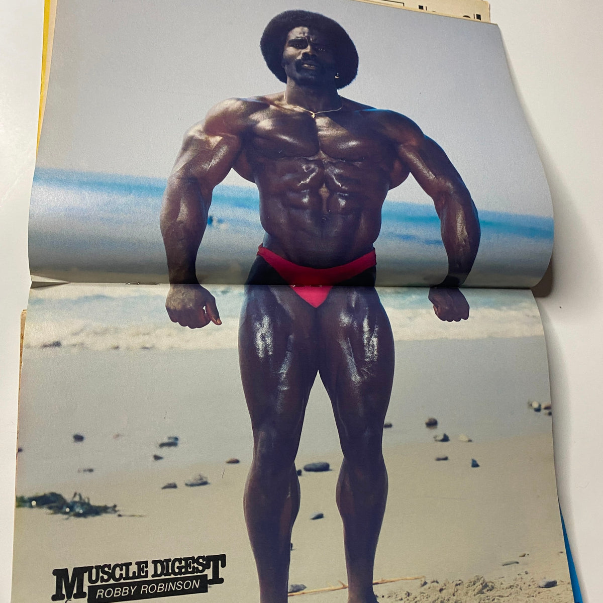 Centerfold spread of Robby Robinson from Muscle Digest Magazine October 1980, showcasing his physique on a beach.