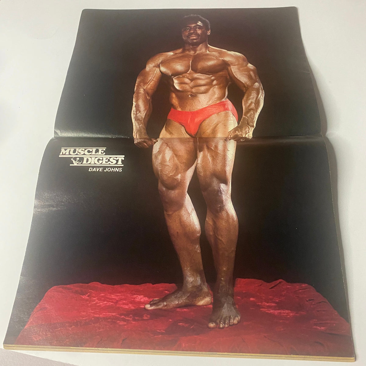 Centerfold of June 1981 Muscle Digest magazine featuring a muscular photograph of Dave Johns in red posing trunks, emphasizing fitness and bodybuilding, under the title "Muscle Digest Magazine June 1981 Dave Johns w Centerfold GD Interior".