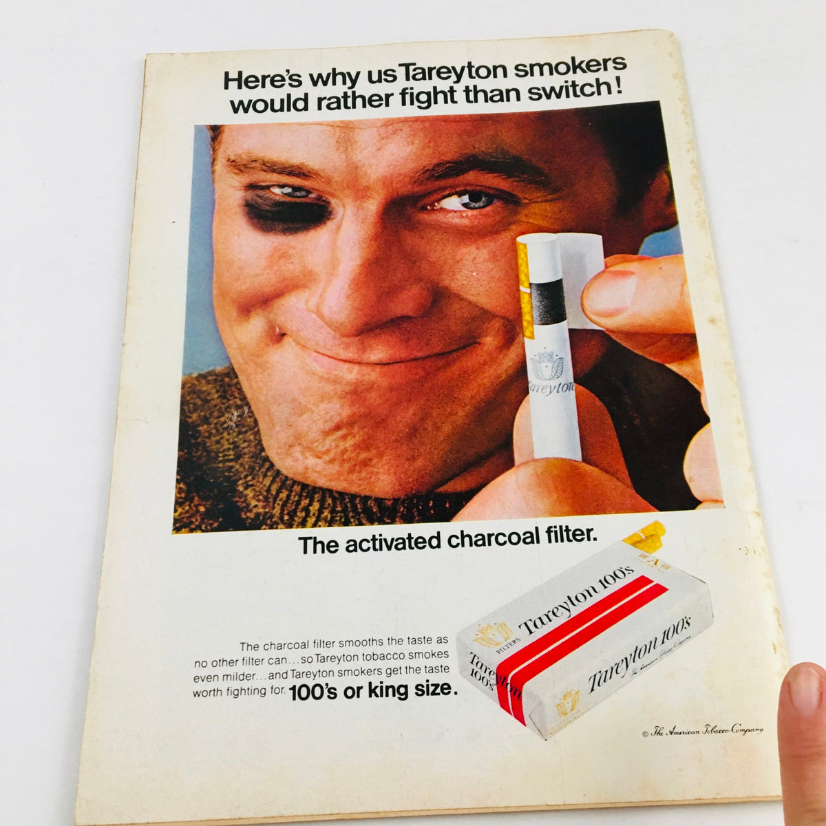 Tareyton Cigarettes Advertisement featuring a man with a black eye, promoting the brand's activated charcoal filter. This vintage ad highlights the slogan 'Here's why us Tareyton smokers would rather fight than switch!' emphasizing the unique selling points of Tareyton cigarettes, related to the Time Magazine May 24 1968 Vol. 91 No. 21 Bobby Kennedy in Cartoonish Photo.