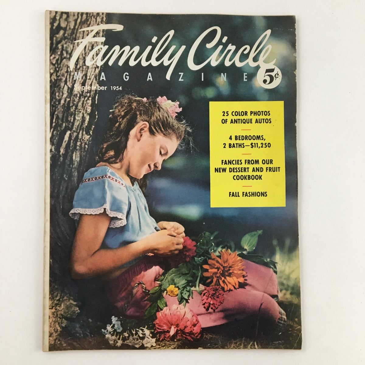 Cover of Family Circle Magazine September 1954 featuring a young girl sitting with flowers, highlighting articles on home design and autumn fashion, and showcasing the magazine's vintage aesthetic.