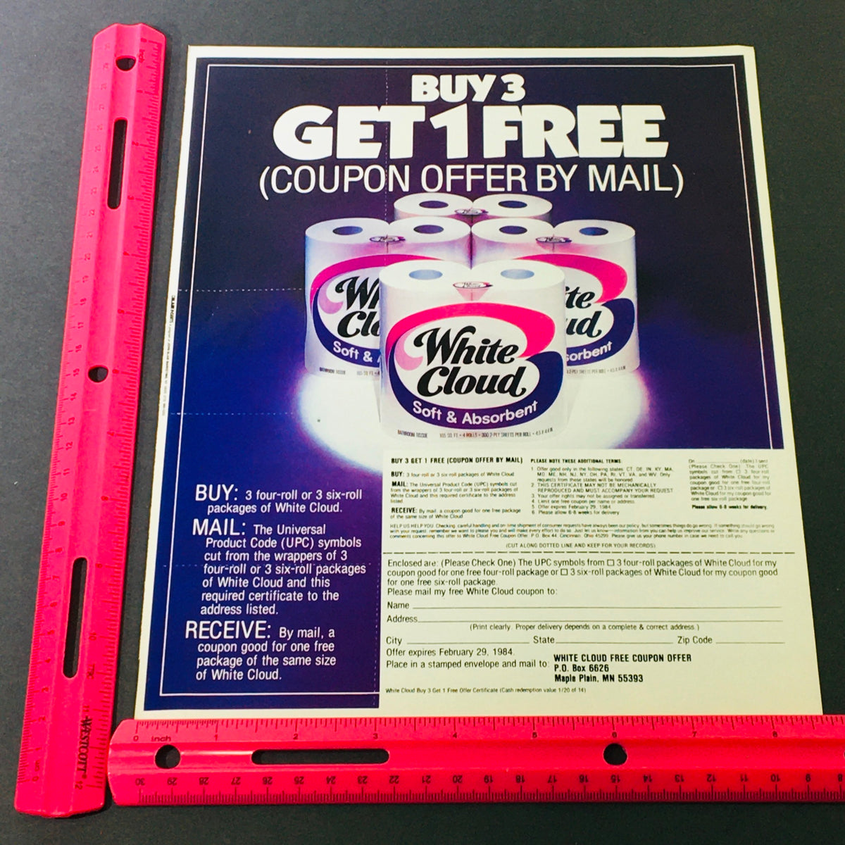 Close-up of the 1984 White Cloud Tissue coupon advertisement with a ruler for size reference, highlighting offers and product details.