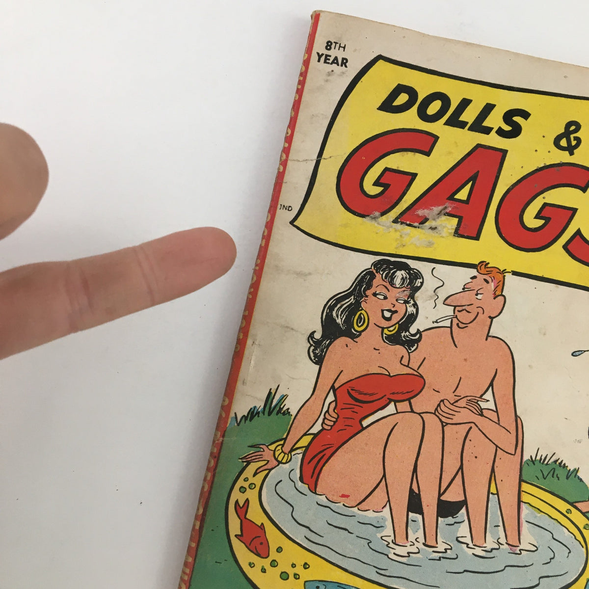 Close-up view of the front cover of Dolls & Gags Magazine October 1958 Vol. 4 No. 7 highlighting colorful artwork and a lighthearted scene with characters in swimwear.