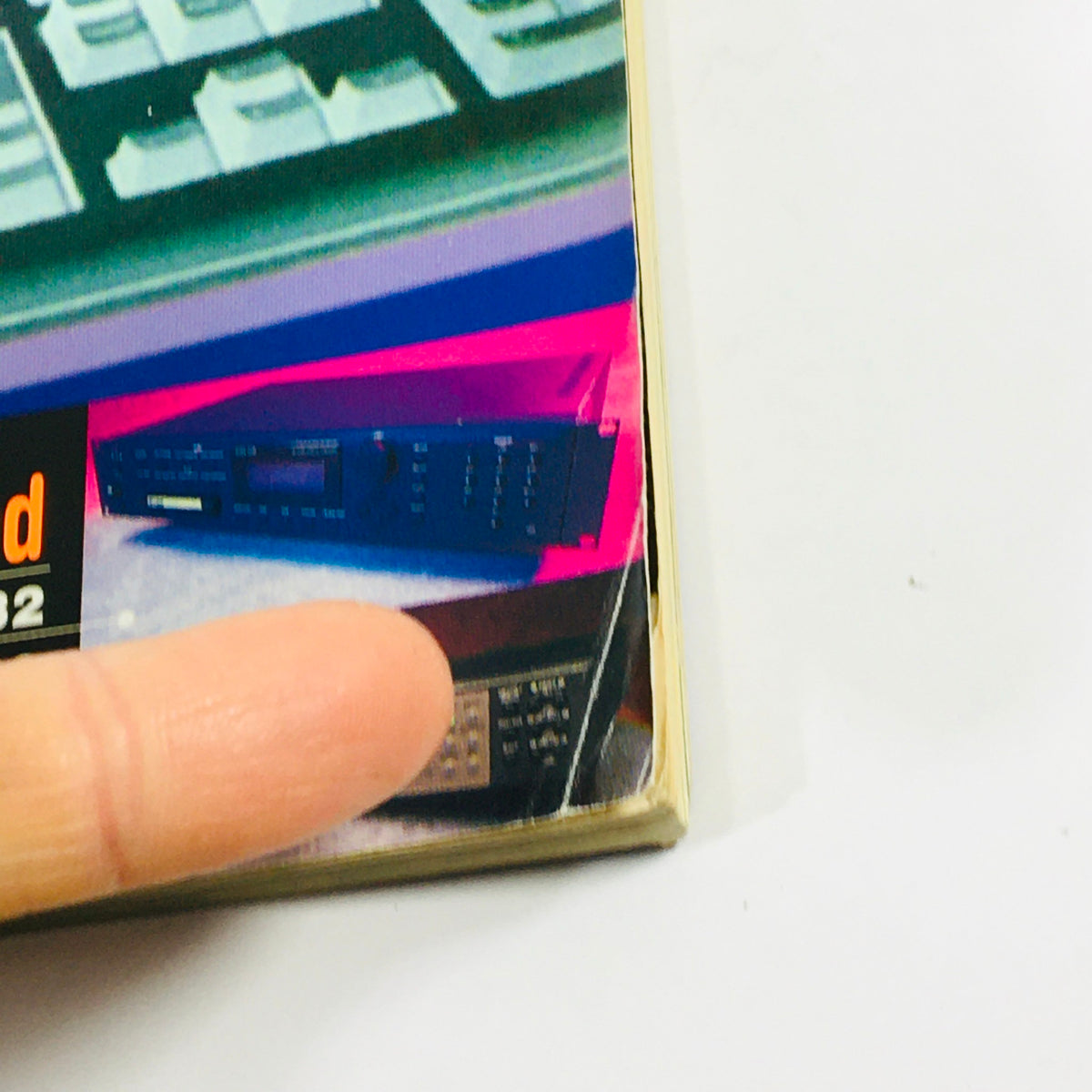 Side view of Keyboard Magazine August 1995 showing a finger pointing to details about E-MU ESI-32 and Yamaha MU80 reviews, capturing the vintage feel of the publication.