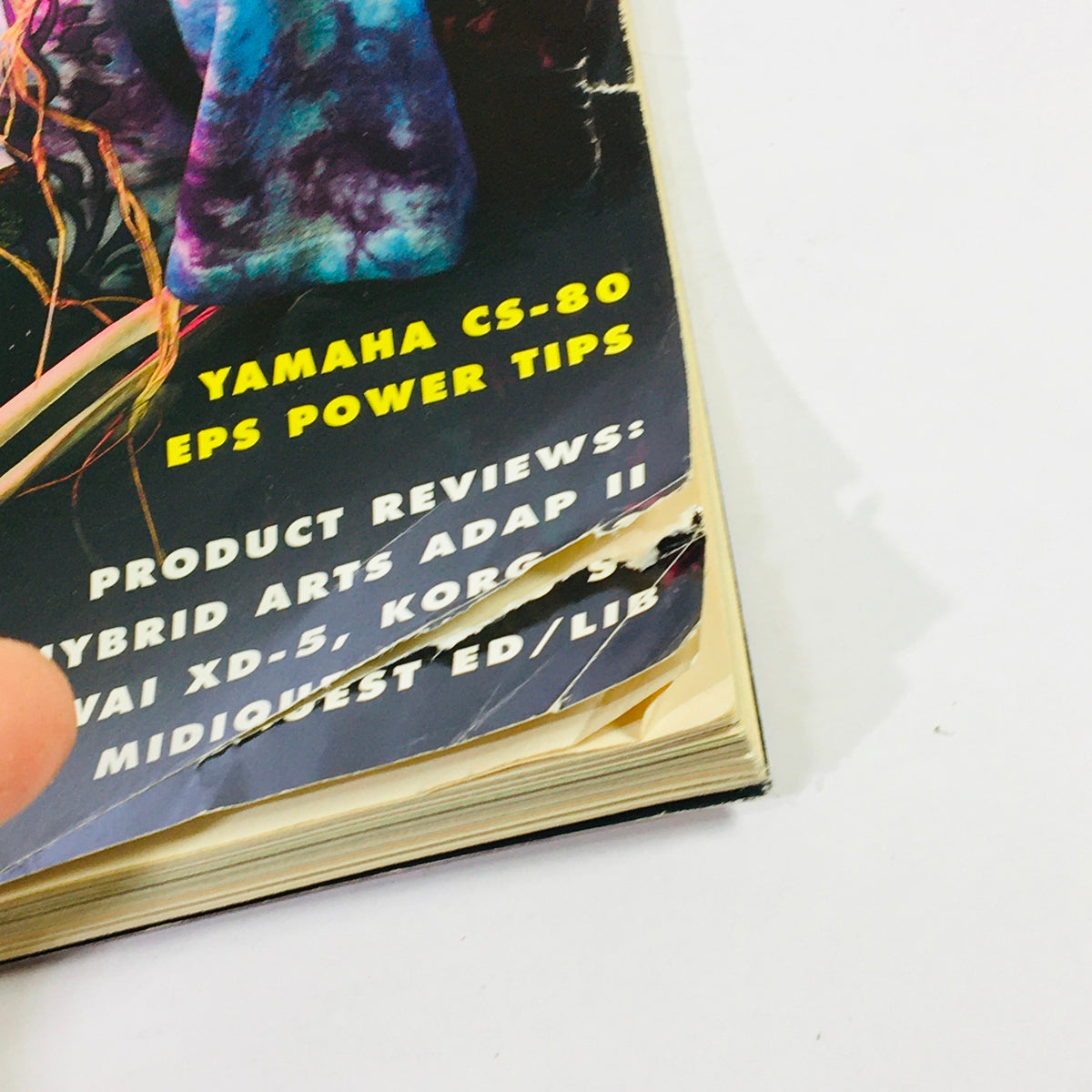 Close-up view of the torn edge of the Keyboard Magazine March 1991, featuring product reviews and tips on Yamaha CS-80 EPS. Highlights the magazine's vintage condition and content related to 90s music keyboard techniques.