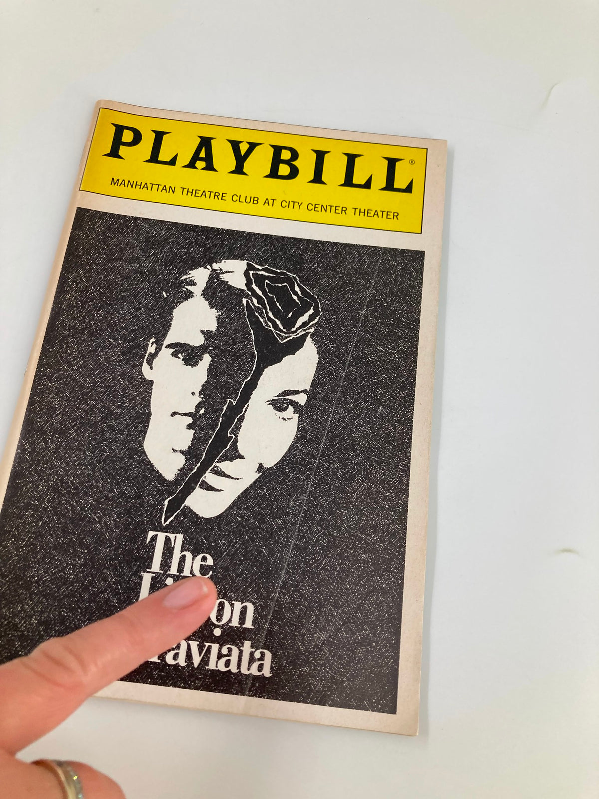 Close-up view of the front cover of the 1989 Playbill for 'The Lisbon Traviata' by Terence McNally, showing a hand pointing at the title with a unique black and white design.