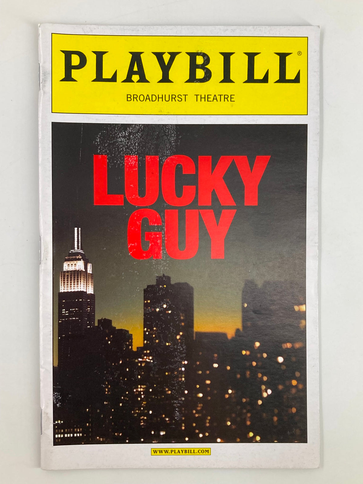 2013 Playbill for 'Lucky Guy' at Broadhurst Theatre featuring a skyline view of New York City, showcasing the iconic Empire State Building in the background.