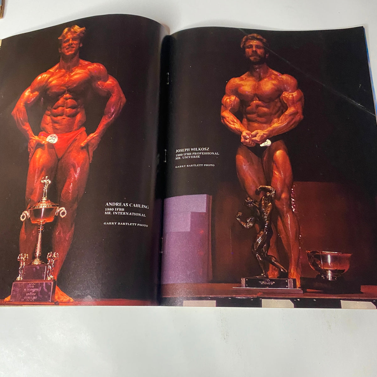 Double-page spread in Muscle Training Illustrated May 1981 featuring bodybuilders Andreas Cahling and Joseph Wilkoyz on stage with trophies.