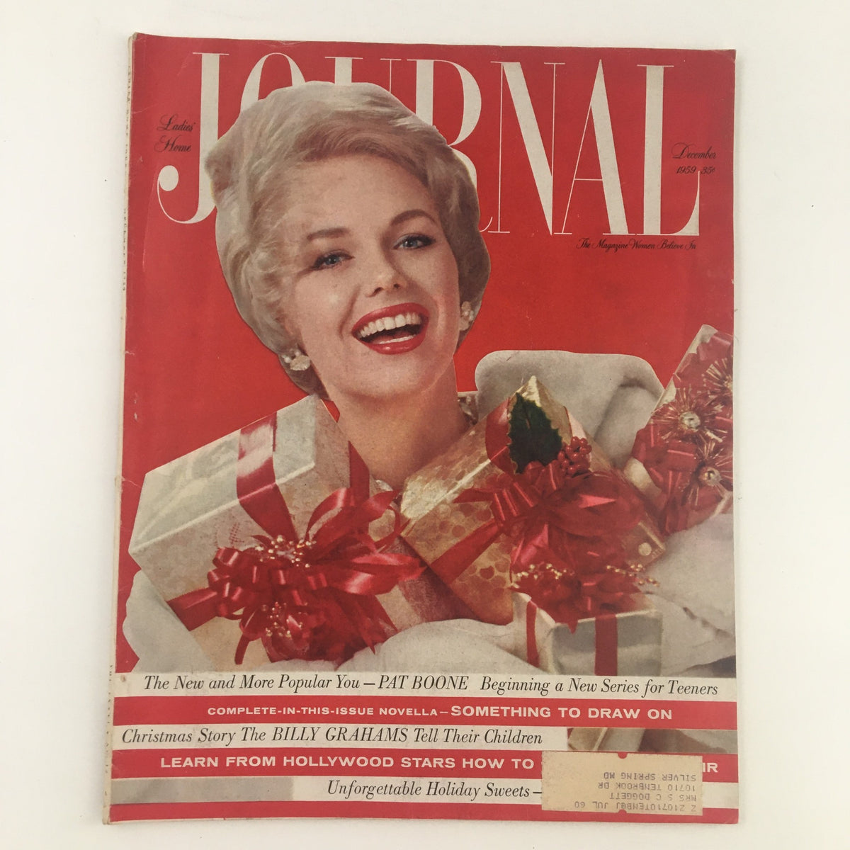 Cover of Ladies' Home Journal Magazine from December 1959 featuring the smiling portrait of a woman with a festive holiday theme, adorned with red ribbons and decorations, highlighting The New and More Popular Pat Boone. This vintage magazine represents mid-20th century culture and nostalgia.