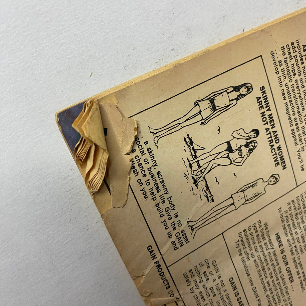 Damaged corner of the back cover of Muscle Up Magazine February 1984 Vol. 6 No. 27 showing wear but still revealing a vintage advertisement regarding bodybuilding.