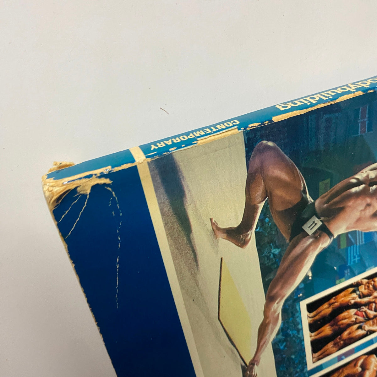 Side view of the 1984 Competitive Bodybuilding book by Joe Weider with Bill Reynolds, showing minor damage on the cover's edge.