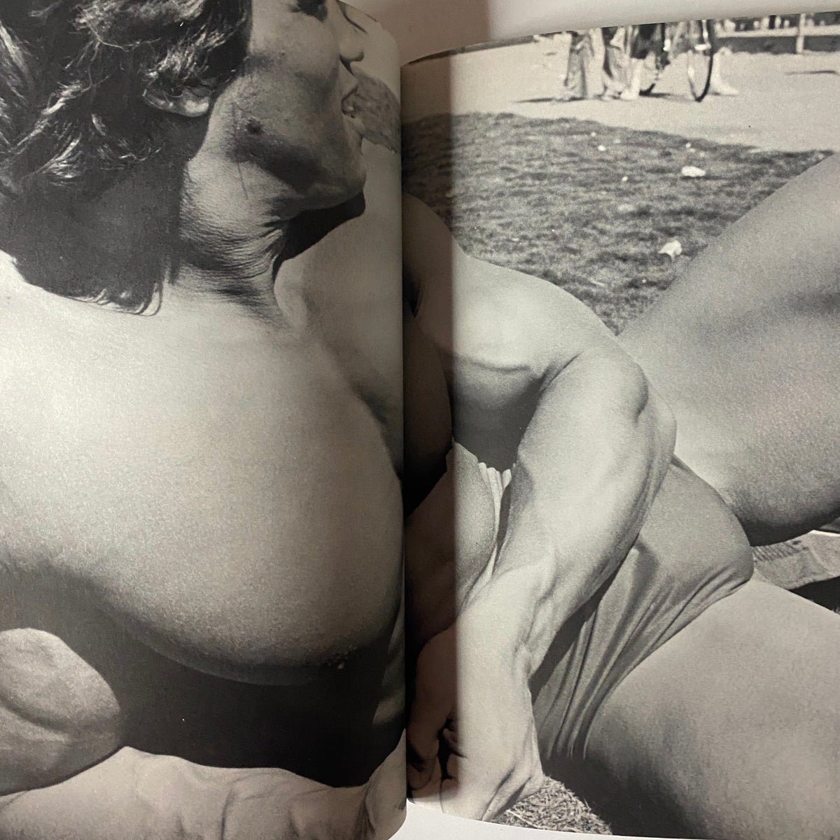 Black-and-white photograph from 'Pumping Iron: The Art and Sport of Bodybuilding', depicting Arnold Schwarzenegger in a relaxed pose during a bodybuilding session.