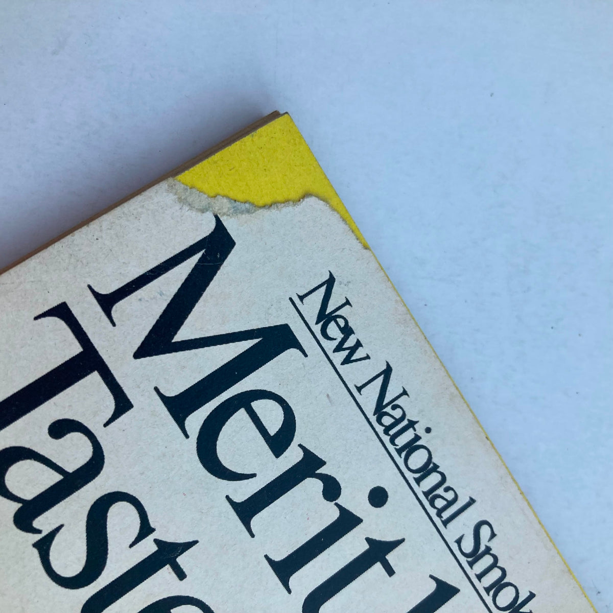 Close-up of the corner of a vintage magazine titled 'Merit Tastes,' showing wear and tear, representing the passage of time with a nostalgic touch.