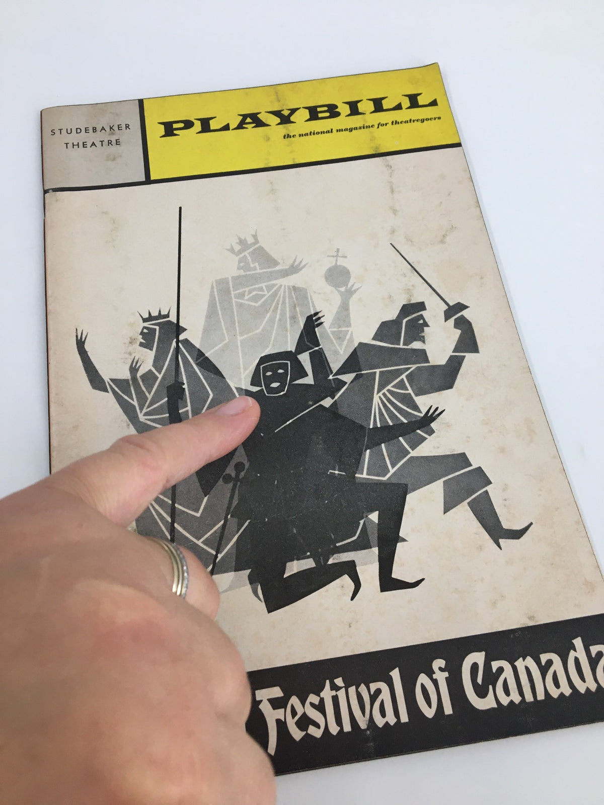 Close-up view of the 1969 Playbill from the Studebaker Theatre with a finger pointing at the central character, representing performances at the Stratford Festival of Canada.