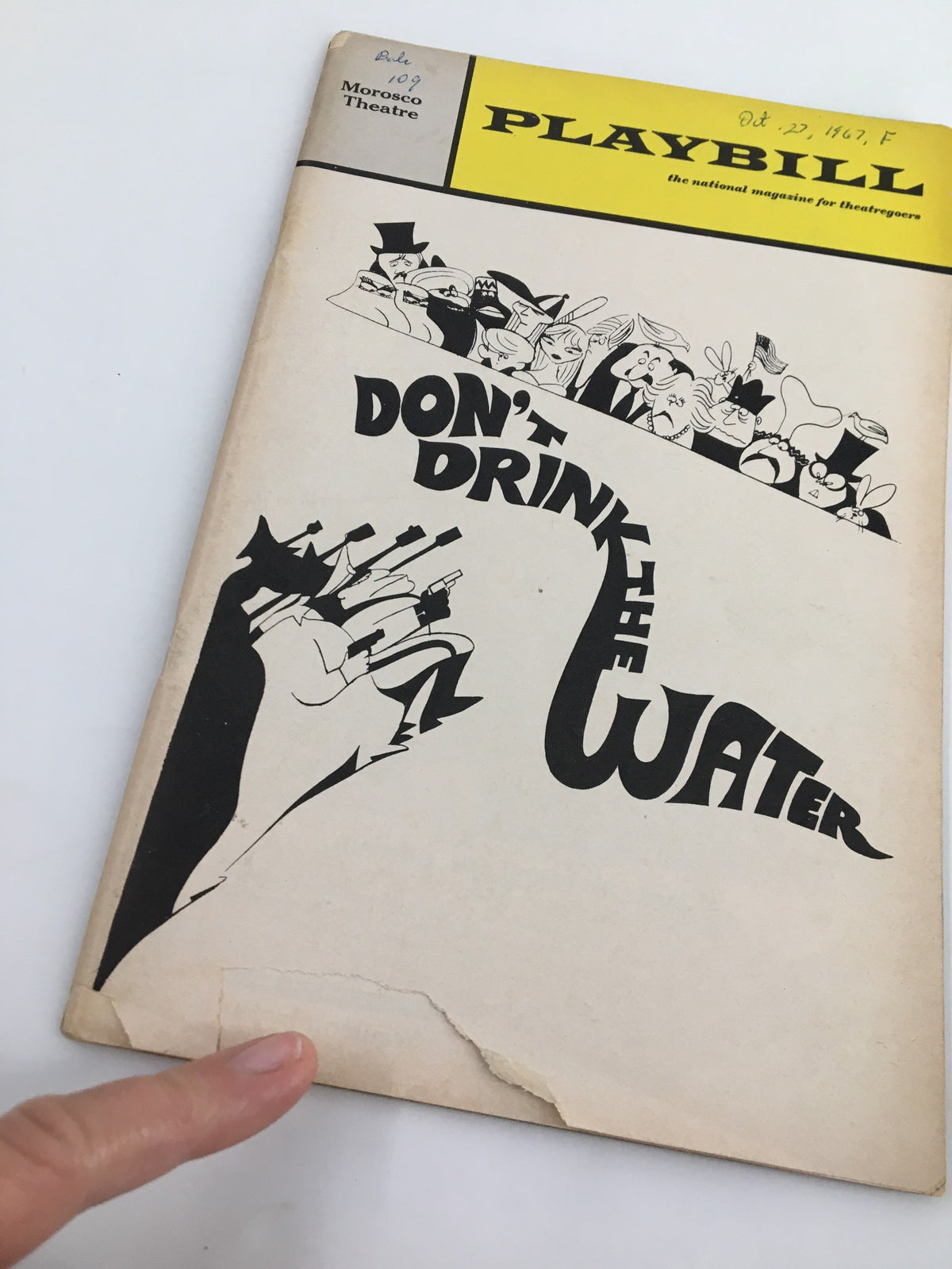 Close-up view of the 1967 Playbill for 'Don't Drink The Water' at The Morosco Theatre, highlighting minor wear and tear, including a visible rip on the cover.