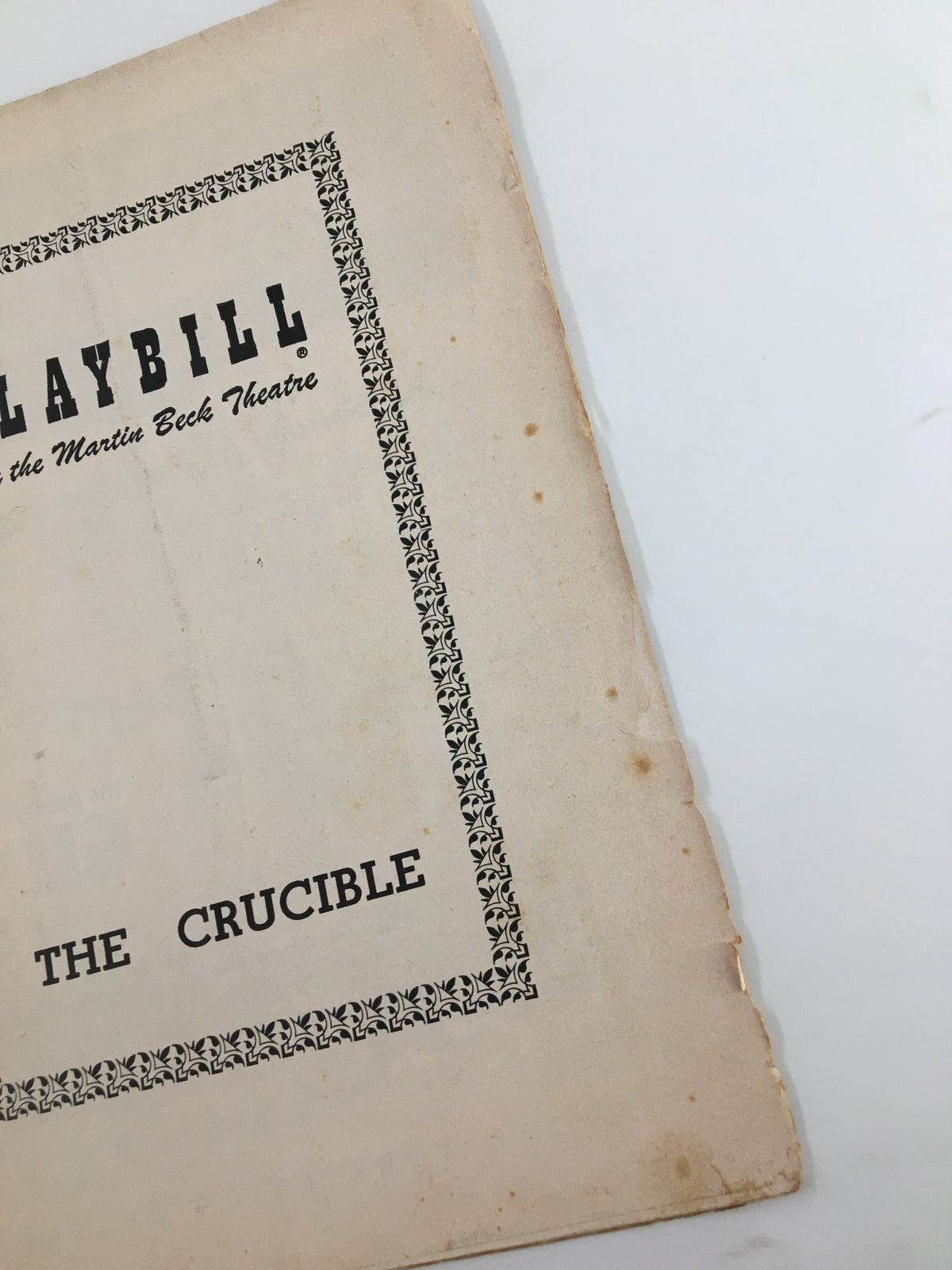 An angled view of the 1953 Playbill for The Crucible at Martin Beck Theatre, highlighting the aged appearance and worn edges.