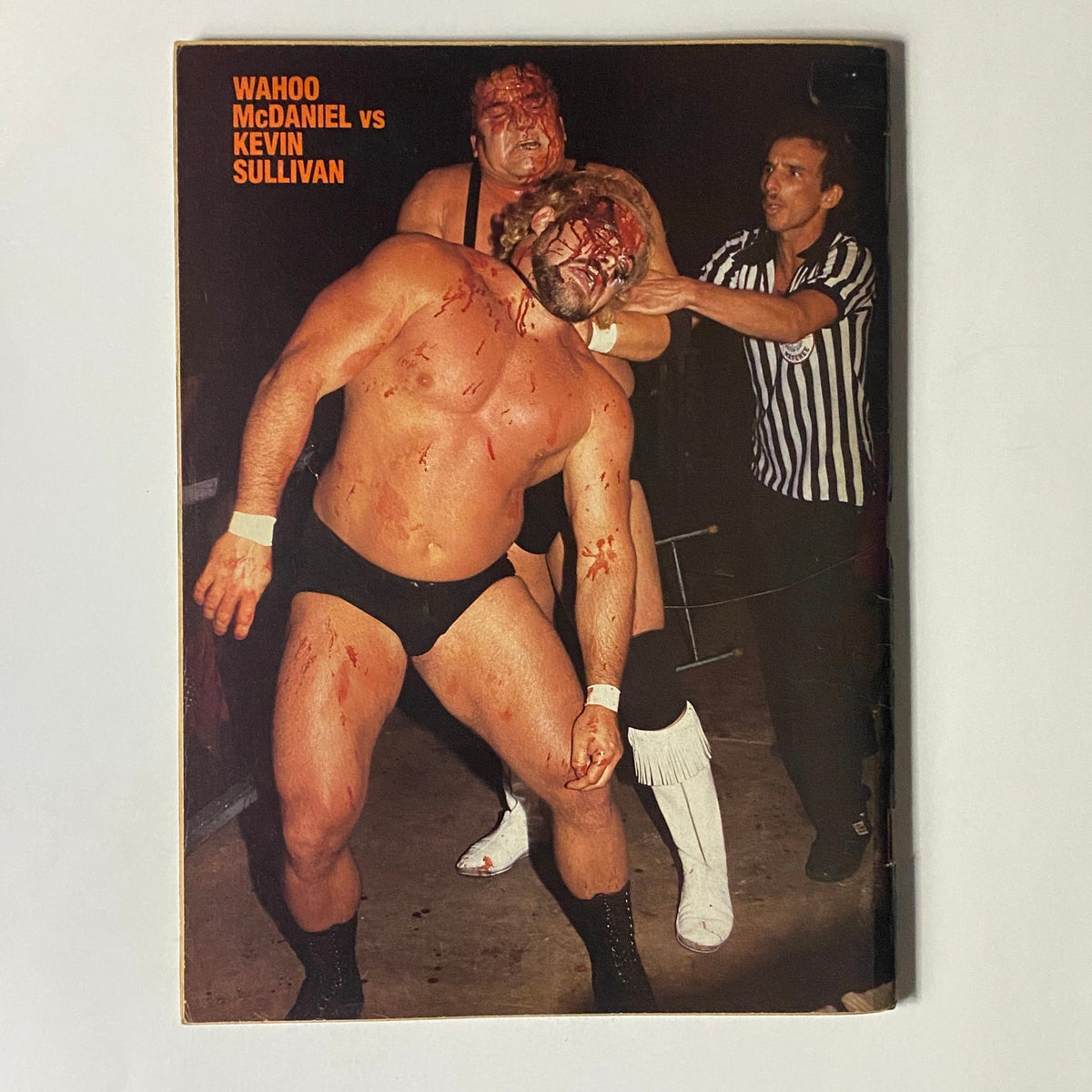 Iconic image from Wrestling Scene Magazine February 1986 depicting a bloody wrestling match between Wahoo McDaniel and Kevin Sullivan, illustrating the intense rivalries of professional wrestling.