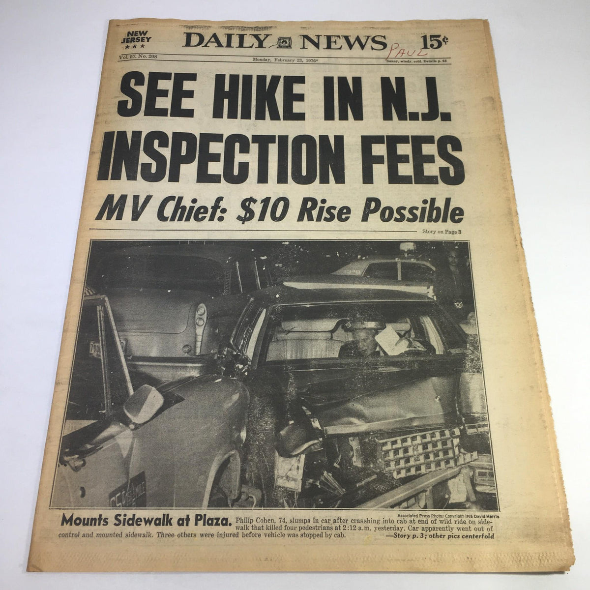 NY Daily News from February 23, 1976, featuring the headline 'See Hike In NJ Inspection Fees; MV Chief: $10 Rise Possible'. The image shows the front page of the newspaper, highlighting issues related to motor vehicle inspection fees in New Jersey. The report includes a description of an accident involving a car on the sidewalk.