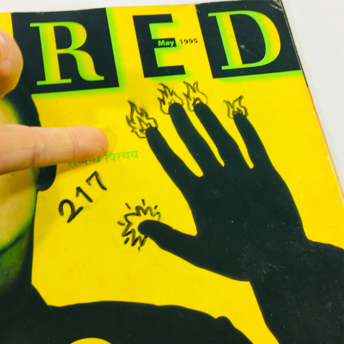 Detail view of the front cover of Wired Magazine May 1995 Vol 3 #5, focusing on the yellow background and Brian Eno's hand with artistic flames, illustrating the magazine's bold design.