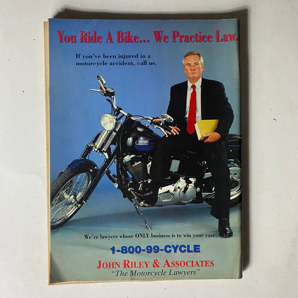 Advertisement in Easyriders Magazine March 1997 featuring a lawyer sitting on a motorcycle with the slogan 'You Ride A Bike... We Practice Law.' promoting services for motorcycle accident victims.