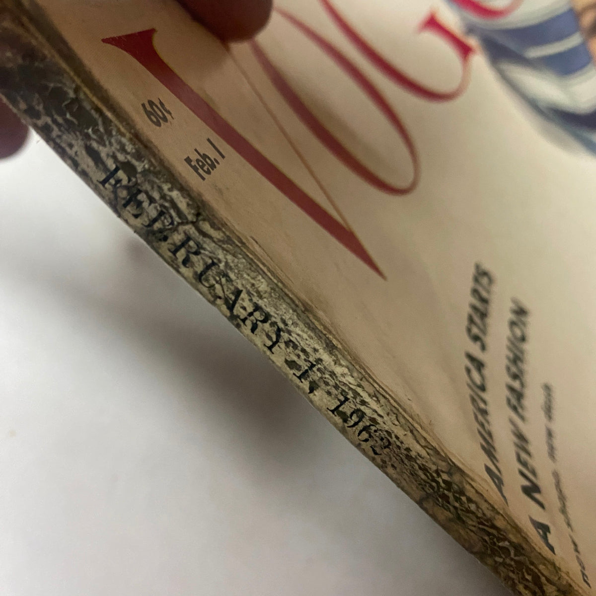 Detailed shot of the cover spine of Vogue Magazine February 1, 1962 with publication date, emphasizing wear and integrity of this vintage piece.