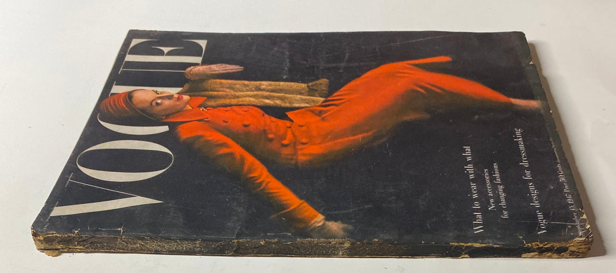 Side view of the September 15, 1947 Vogue Magazine cover showing a model in a striking red coat. The image highlights the magazine's vintage condition, with visible wear, including a worn spine.