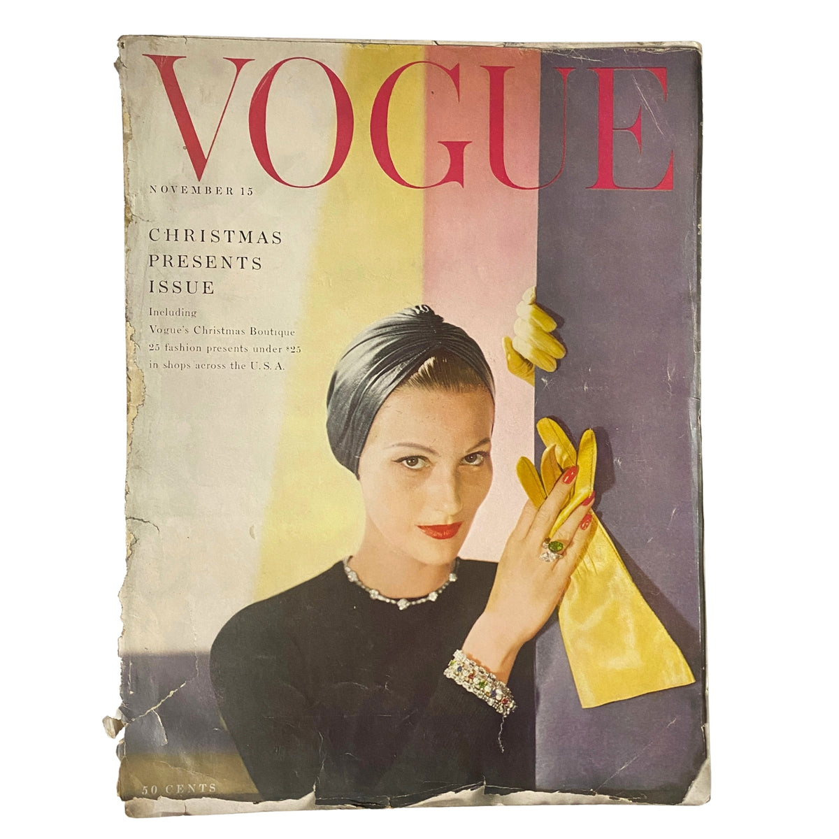 Vogue Magazine cover from November 15, 1954 featuring Mary Jane Russell. The image showcases a model wearing a headscarf, adorned with striking gloves and jewelry, illustrating mid-century fashion and holiday glamour.