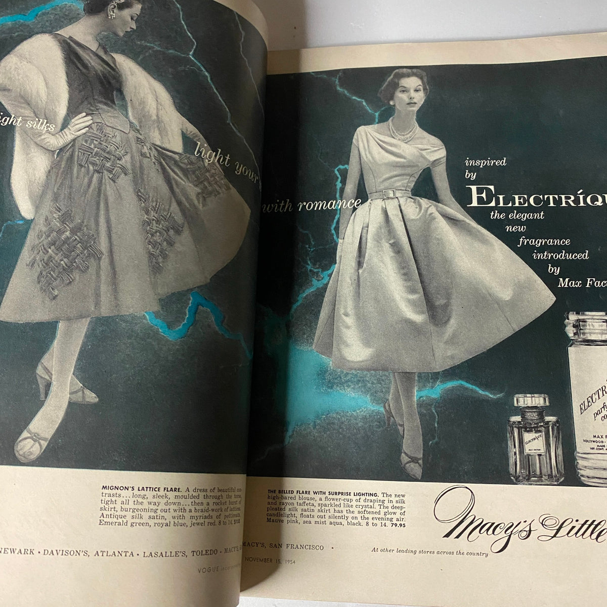 A vintage advertisement from Vogue Magazine November 15, 1954 featuring a model in an elegant dress alongside the text promoting the 'Electrique' fragrance by Max Factor. The image showcases mid-century fashion and glamour.