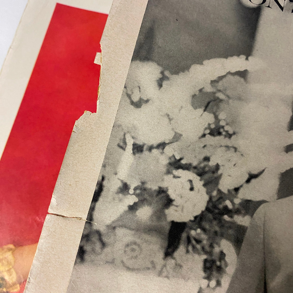 A close-up of the edge of a vintage magazine page from Vogue Magazine March 1, 1960, showing signs of wear with a torn area, highlighting the magazine's age and vintage charm.