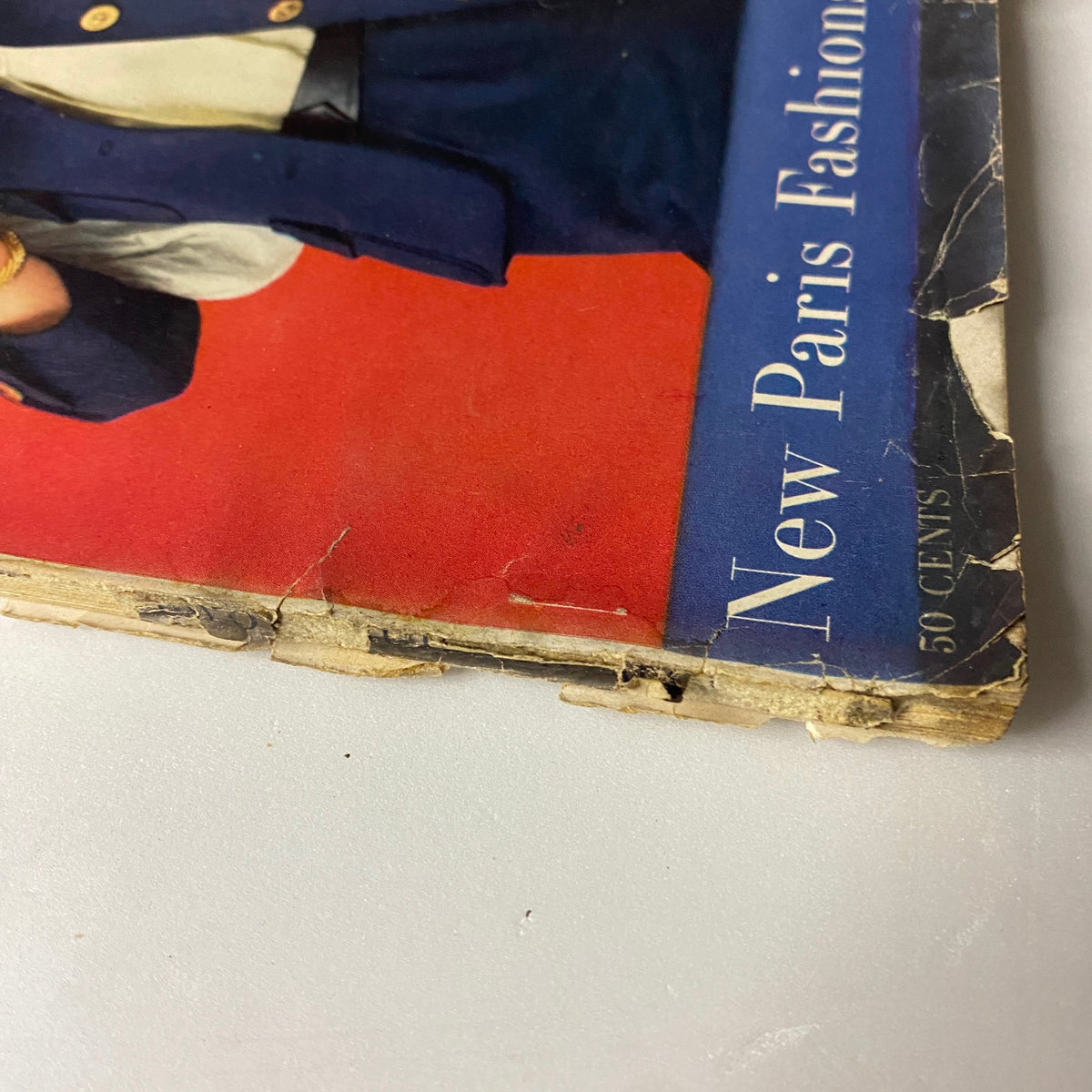 Detail shot of Vogue Magazine March 15, 1957 cover highlighting 'New Paris Fashion' with a worn corner, ideal for collectors of vintage fashion magazines.