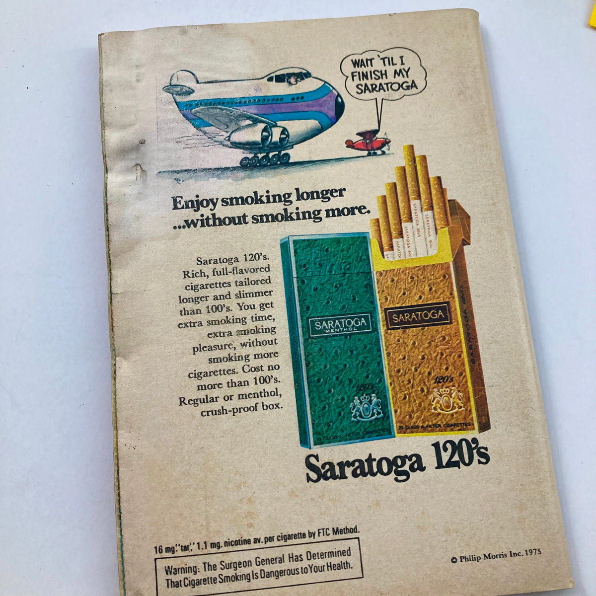 Advertisement page from TV Guide Magazine November 22, 1975, issue #1181 promoting Saratoga 120's cigarettes, showcasing a whimsical airplane graphic.