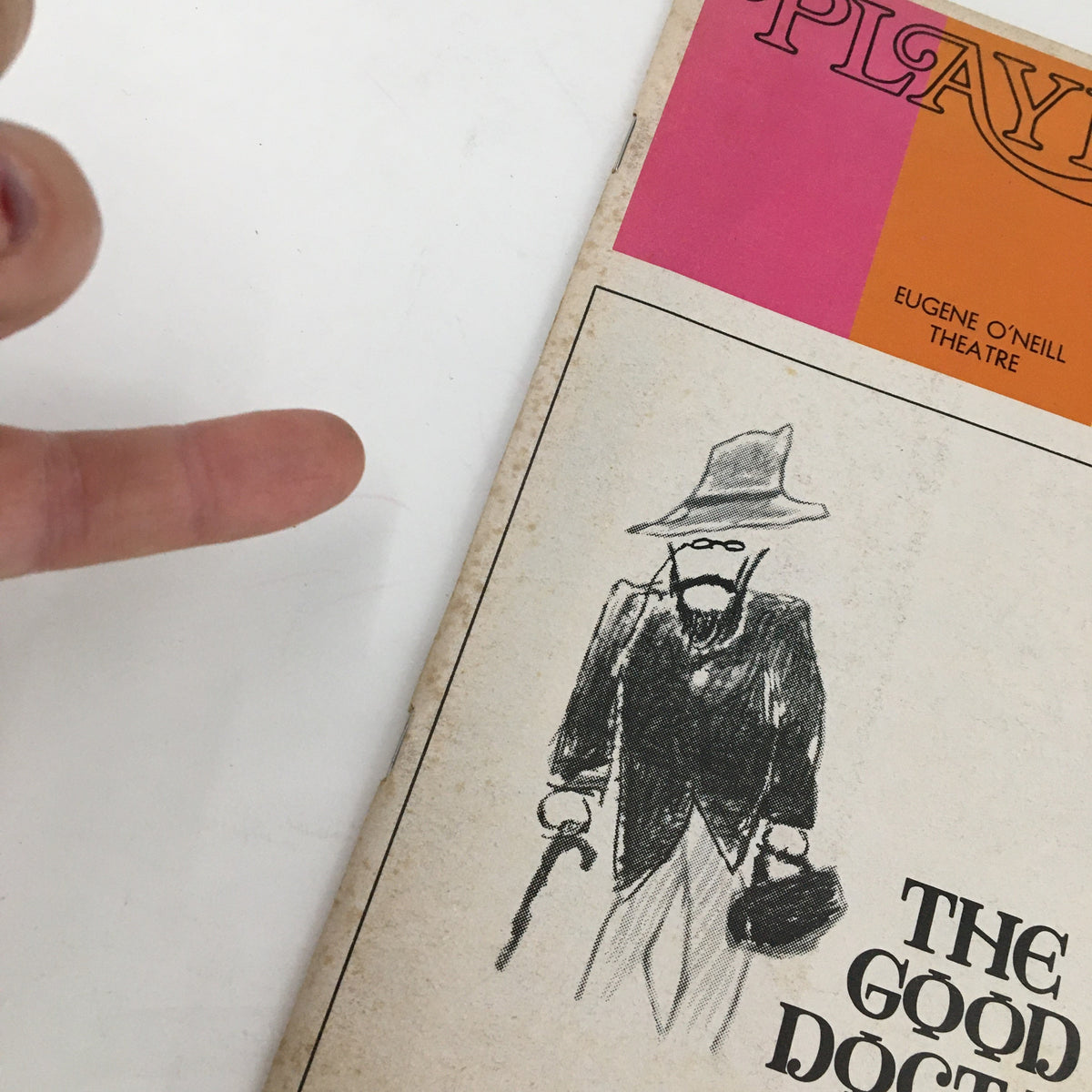 A close-up view of the 1973 Playbill for The Good Doctor, highlighting a hand pointing at an illustration of a character, featuring Christopher Plummer.