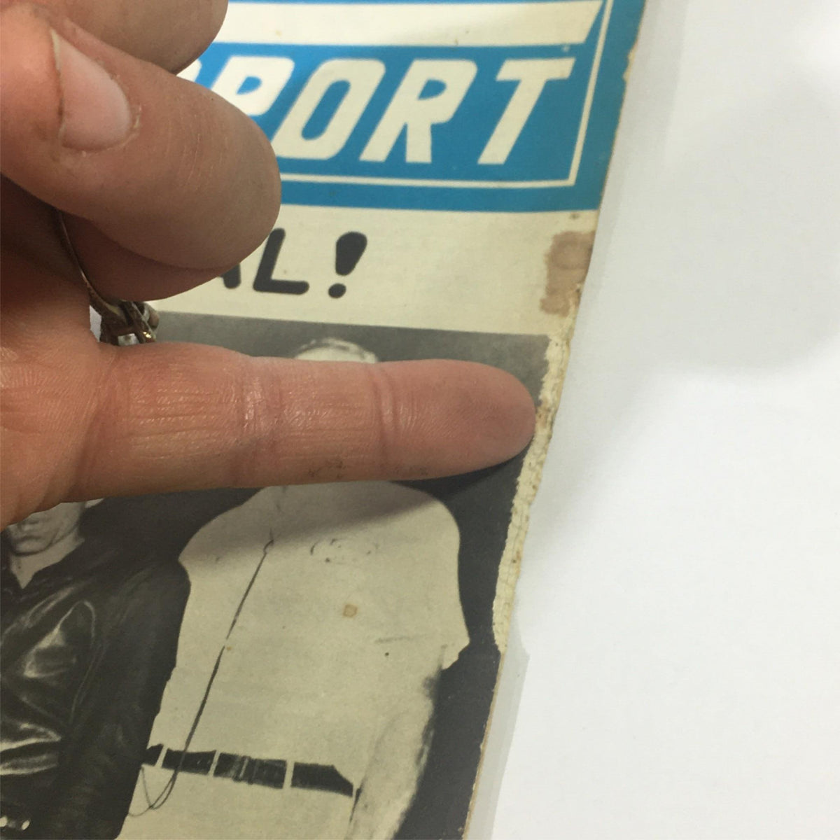 Detailed view of VTG Cycle Sport Magazine March 1961 with a finger pointing to the wear and tear, illustrating its vintage condition.