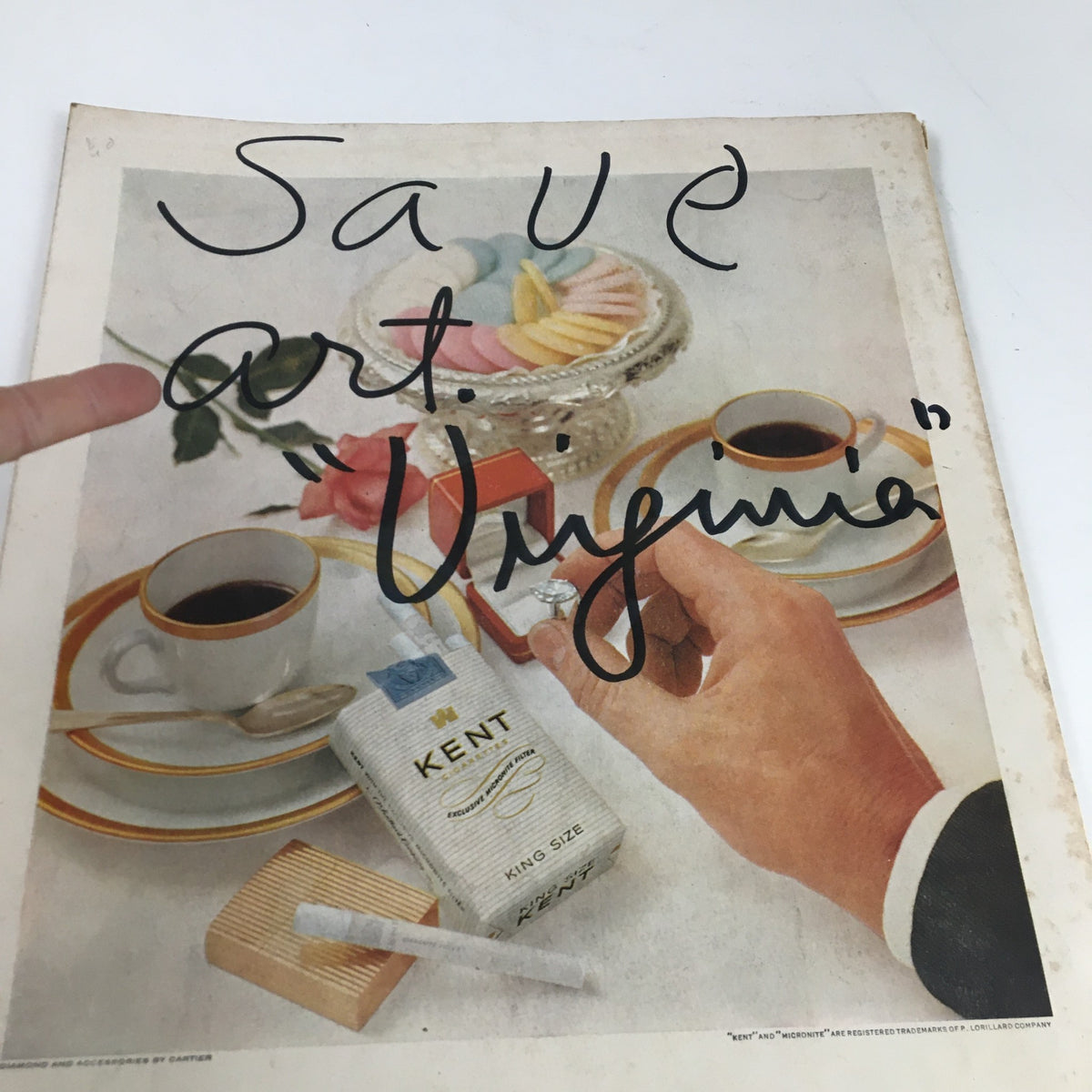 Advertisement page from Holiday Magazine November 1955 with a close-up of a hand holding an item next to a coffee cup and colorful sweets, marked 'Save art. Virginia'.