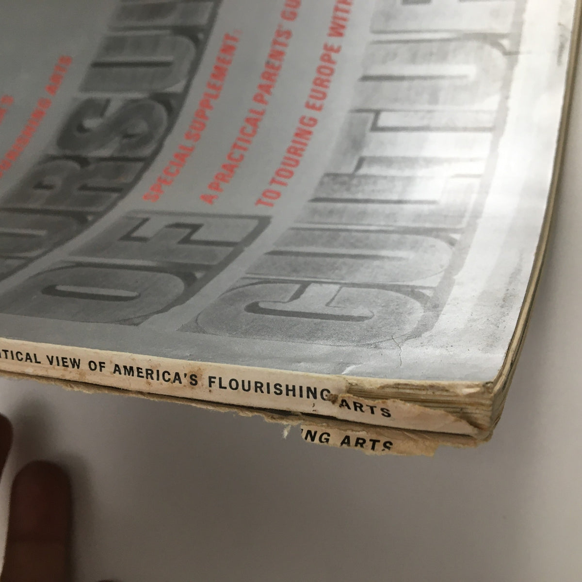 Close-up view of the spine of Holiday Magazine March 1966 displaying the text 'A Critical View of America's Flourishing Arts,' indicating wear consistent with age.
