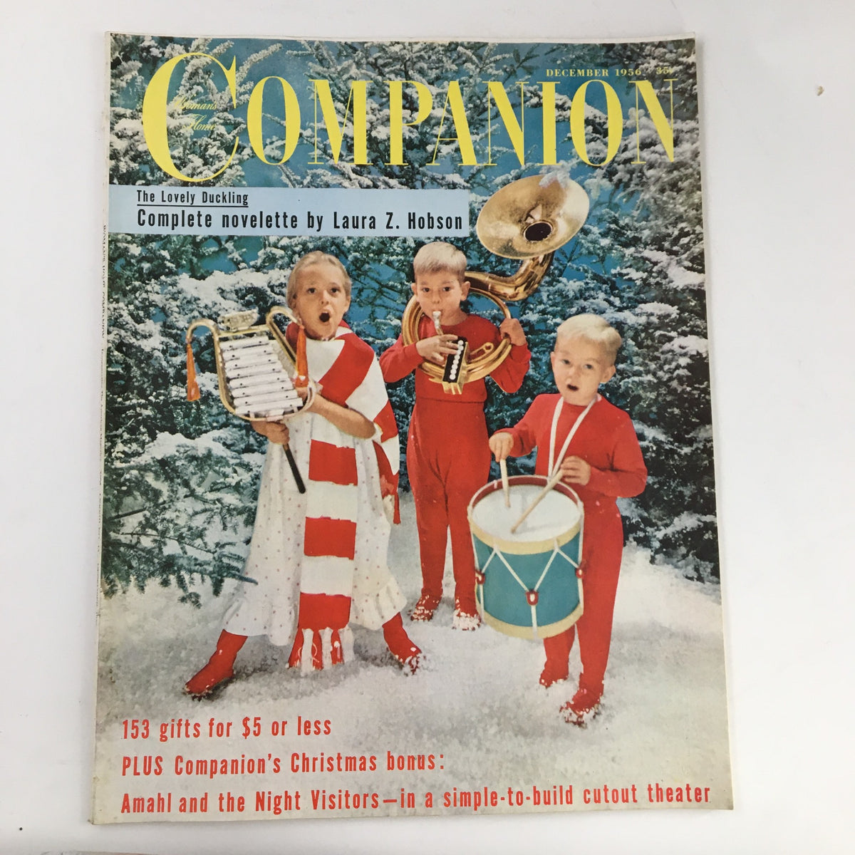 Cover of Woman's Home Companion Magazine December 1956 featuring children in festive attire and musical instruments, showcasing the theme of holiday gifts and 'Amahl & The Night Visitor'.