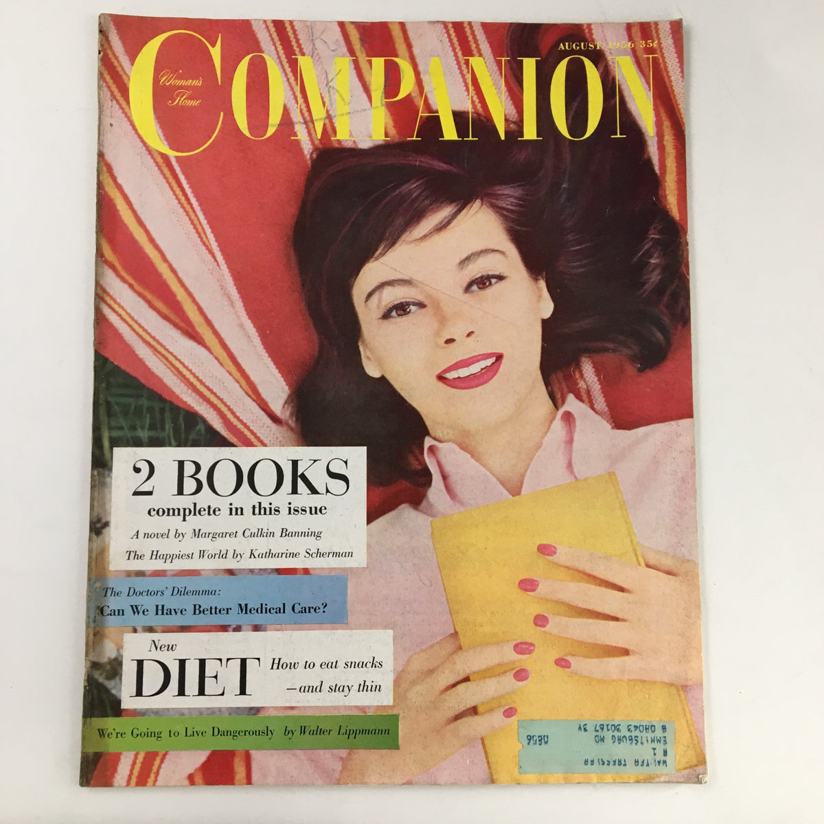 Cover of Woman's Home Companion Magazine August 1956 featuring a woman with dark hair and pink nails holding a yellow envelope, showcasing tips on how to eat snacks and stay thin.