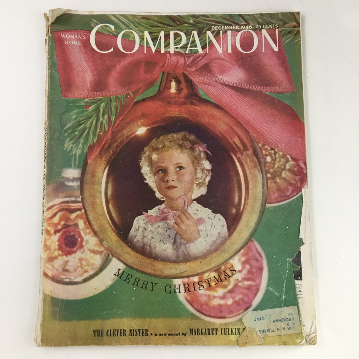Cover of Woman's Home Companion Magazine December 1946 featuring a young girl with a candy cane inside a Christmas ornament, adorned with a large pink ribbon, capturing holiday spirit.