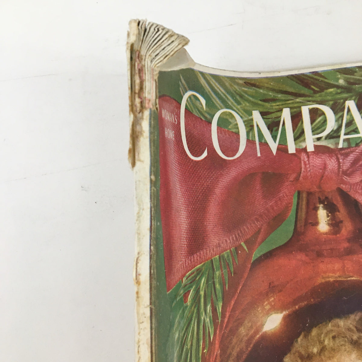Side view of Woman's Home Companion Magazine December 1946 showing the spine and the vibrant festive colors of the cover with a pink ribbon and holiday decorations.