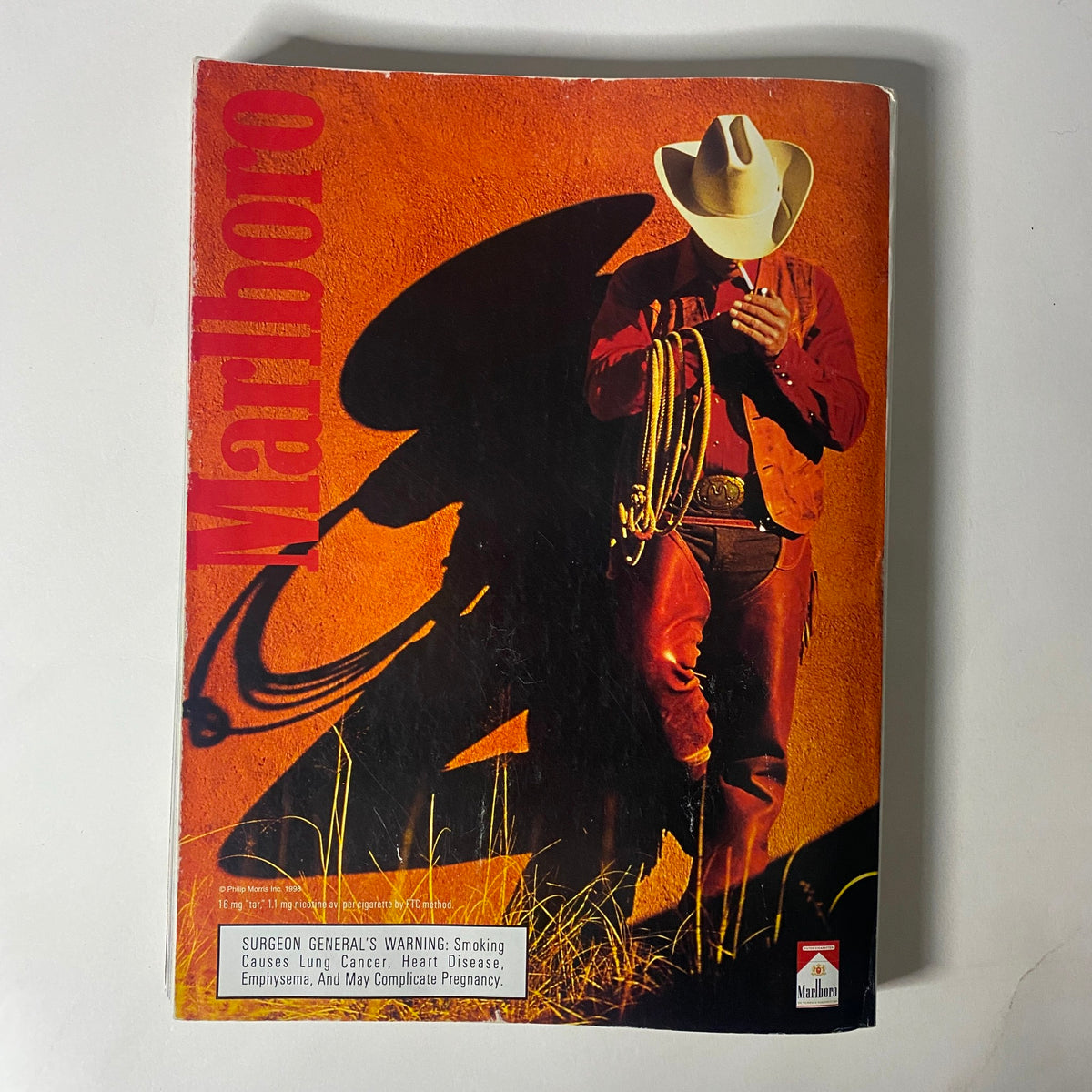Cover of a Marlboro advertisement showcasing a cowboy in traditional Western attire, representing ruggedness and the essence of outdoor lifestyle, part of Vogue Magazine March 1998.