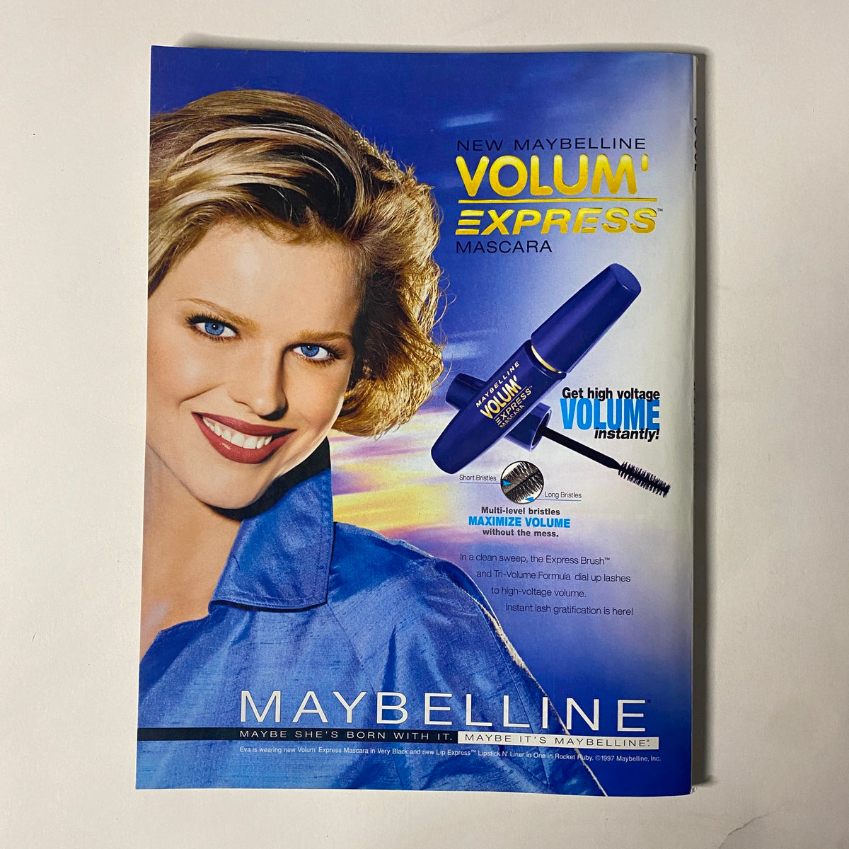 Maybelline Volum' Express Mascara advertisement featuring a smiling model promoting high-volume eyelashes, emphasizing beauty and confidence with the tagline 'Maybe she's born with it, maybe it's Maybelline'.