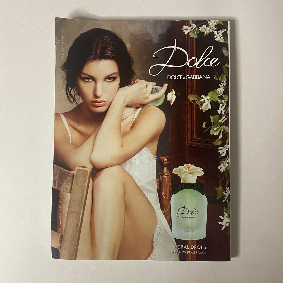 Dolce & Gabbana Dolce Floral Drops Perfume Advertisement featuring a model casually resting with the perfume bottle on a wooden chair, showcasing the product's elegant design and floral theme. Vogue Magazine April 2015 Serena Williams Cover No Label VG.