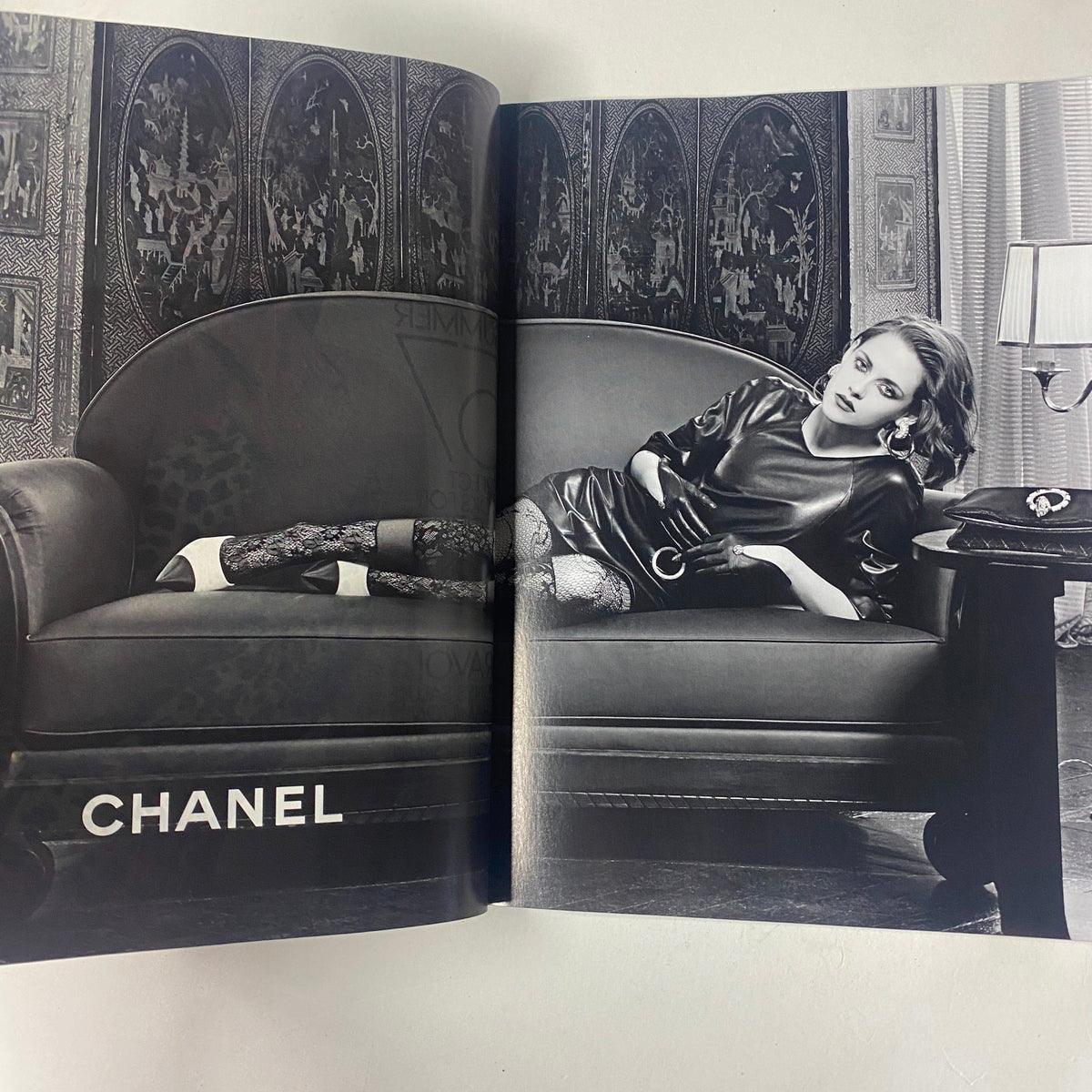 Vogue Magazine June 2016 Margot Robbie Cover showcases a striking black and white image featuring a model lounging on a couch, wearing Chanel fashion accessories, emphasizing luxury and elegance.