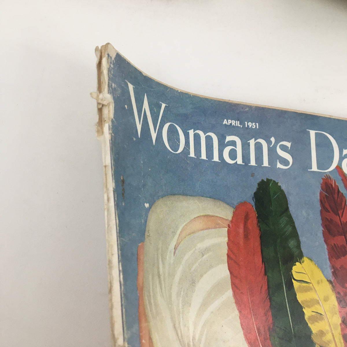 Close-up view of the Woman's Day Magazine April 1951 cover, showcasing the magazine's title and vibrant feathered headdress illustration.