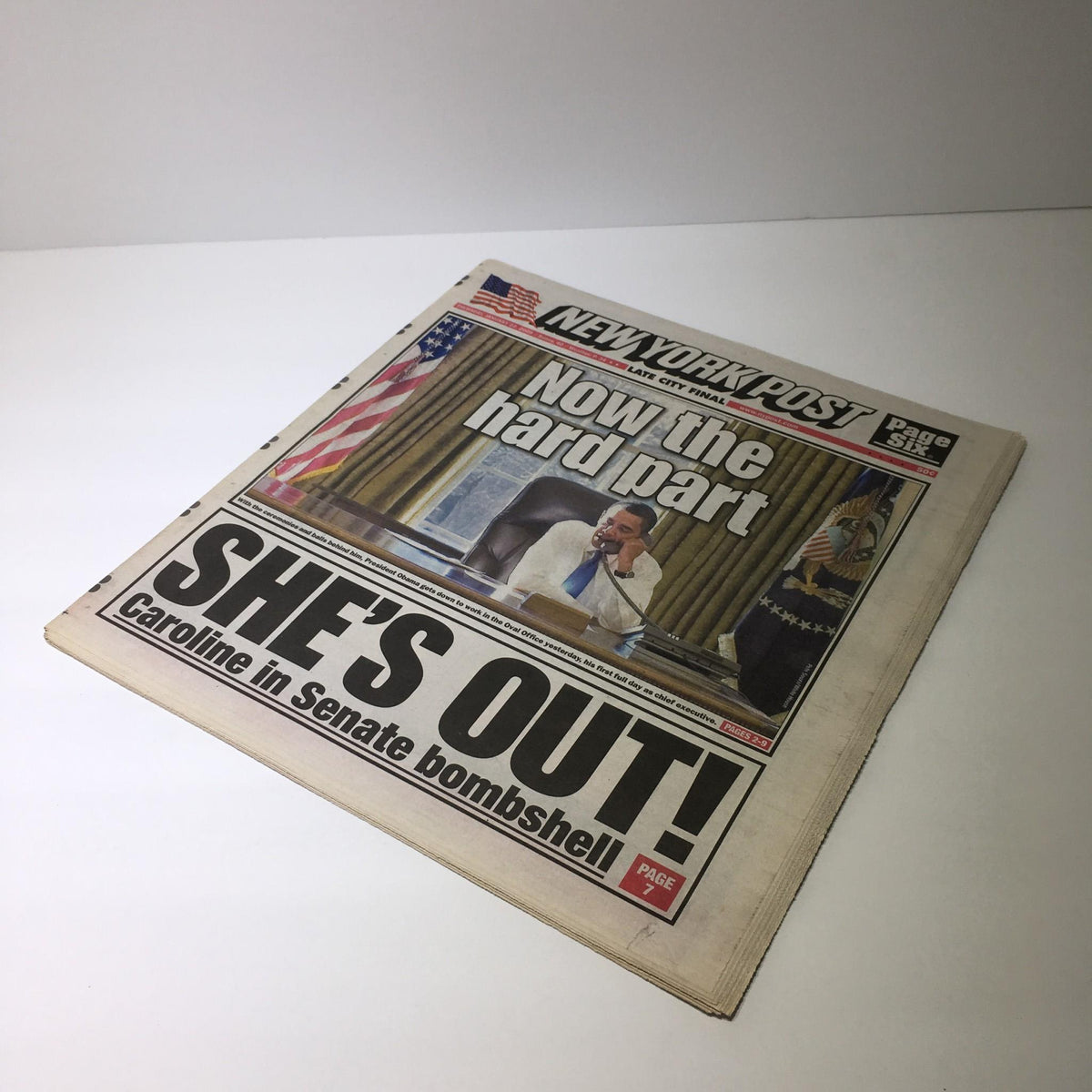 Angled view of the New York Post featuring the headline 'Now the hard part, She's Out!' with a focus on the photograph of a man sitting in an office, January 22, 2009.