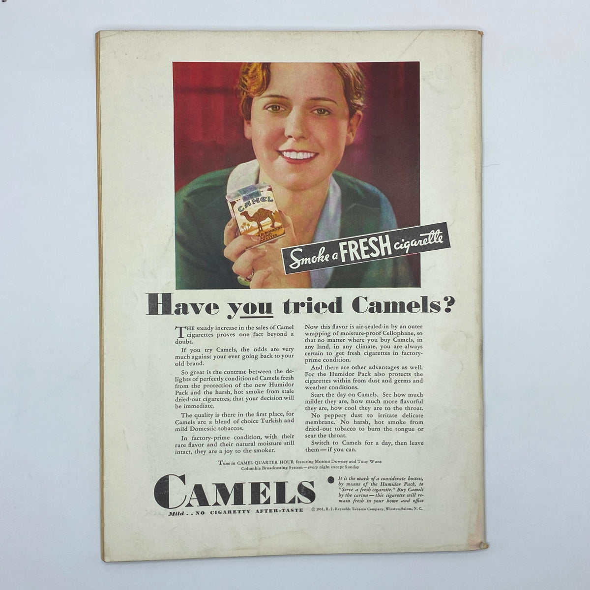 Vintage advertisement for Camel cigarettes in The New Yorker magazine October 3, 1931, featuring a smiling woman holding a pack of Camel cigarettes.