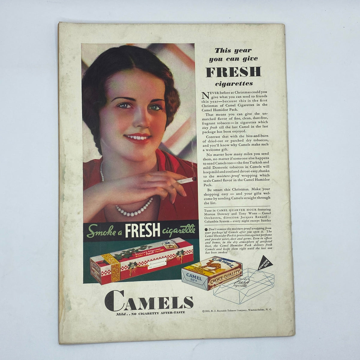 Vintage advertisement for Camels cigarettes from The New Yorker magazine December 26, 1931 featuring a smiling woman holding a cigarette. The ad promotes the freshness of Camel cigarettes, showcasing the marketing style of the time.