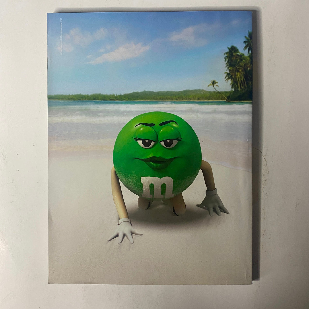Visual from Sports Illustrated Magazine Winter 2011 showcasing a playful M&M's character on a beach setting, adding a fun touch to the swimsuit edition.