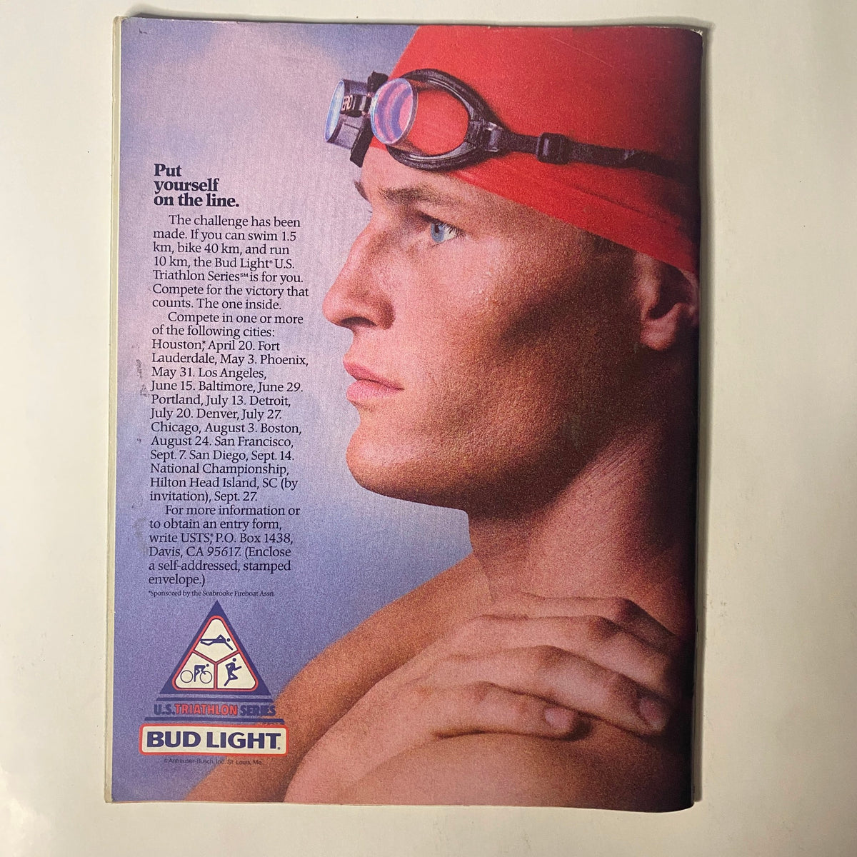 Advertisement in TriAthlete Magazine May 1986 for Bud Light, featuring a male swimmer wearing a red swim cap and goggles, promoting upcoming triathlon events.